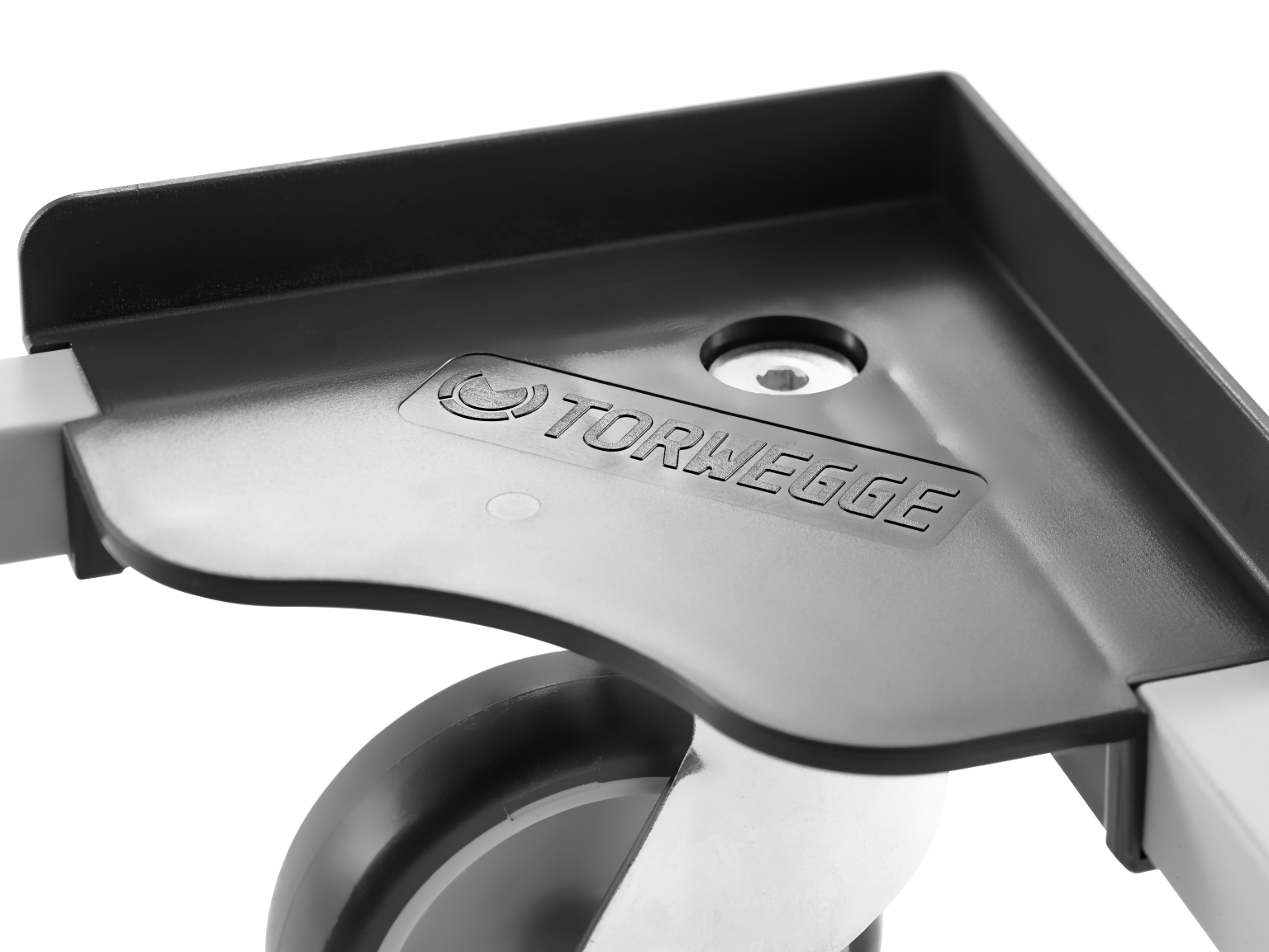A close-up view of a black plastic component featuring the embossed name -TORWEGGE.- It appears to be part of a machinery assembly, with a circular opening and a cylindrical element visible below.