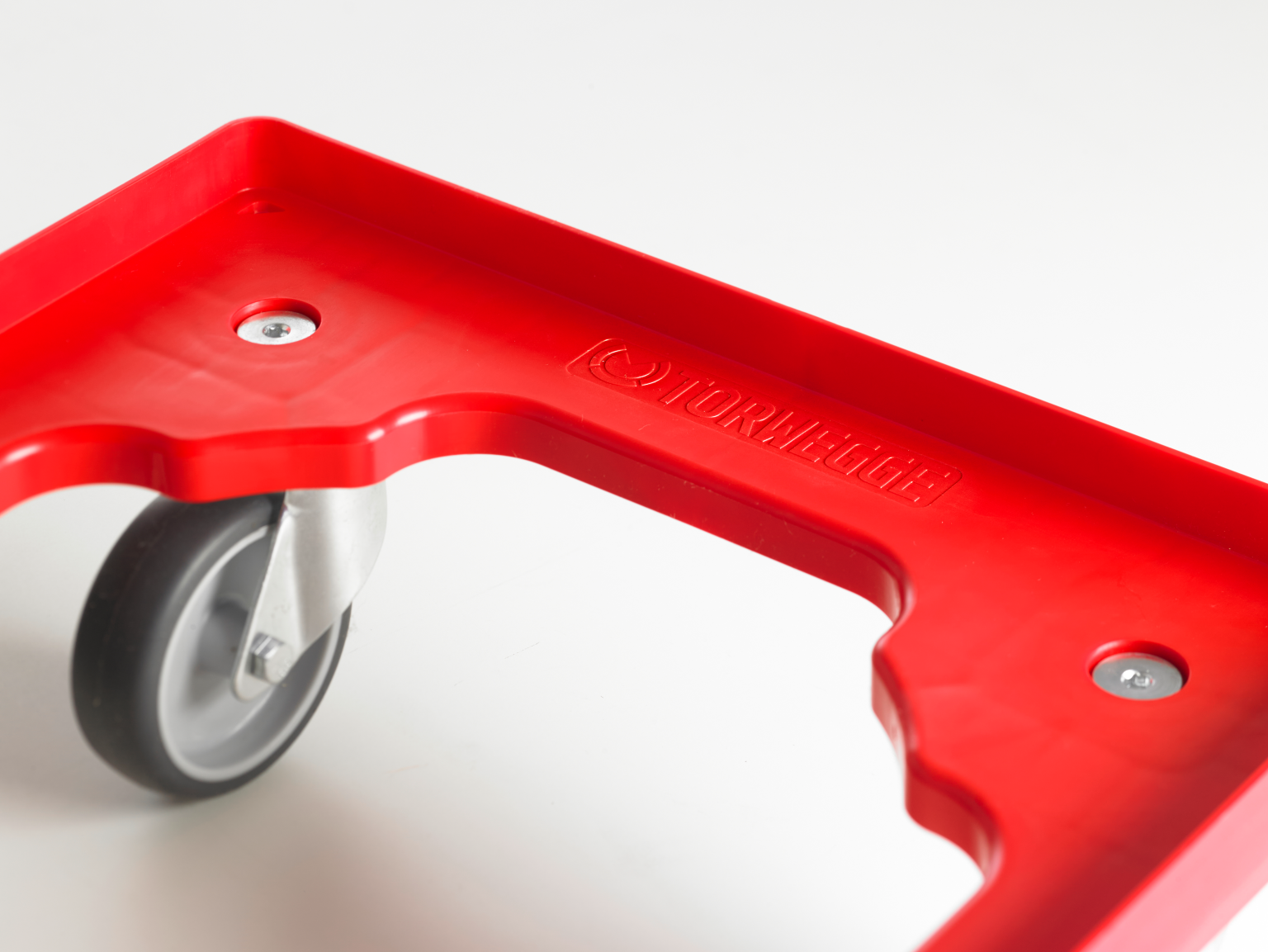 A bright red platform with a cutout shape features a mounted swivel wheel. The surface appears to be made of durable plastic. The branding -TORWEGGE- is embossed on the edge.