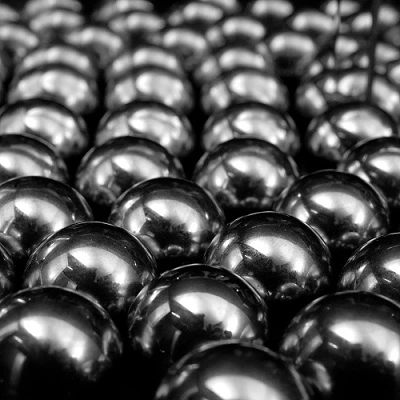 Kugeln aus glänzendem Metall liegen dicht nebeneinander auf einer Fläche. Ihre runde Form reflektiert die Umgebung, was eine gleichmäßige und symmetrische Anordnung schafft. Der Hintergrund ist schwer zu erkennen.