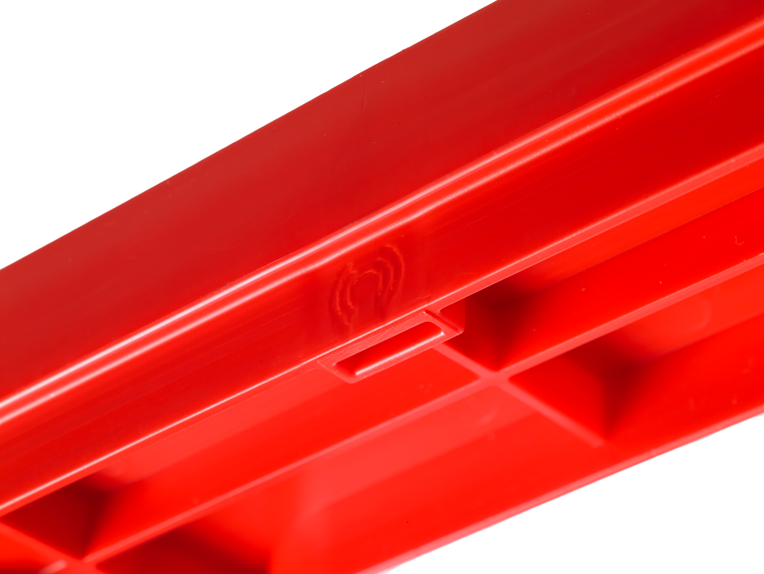 A bright red plastic component features several compartments and a smooth finish. It is likely designed for storage or organization, positioned against a plain background.